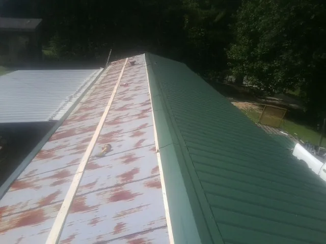 Old rusted panels beside newly installed green metal roofing — Wind Damage Roof Repair by Roofing Brothers in Fallsburg