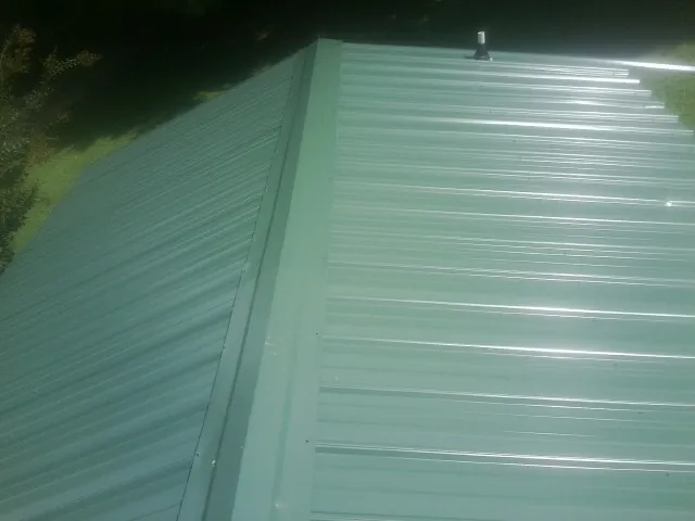 New green metal panels meeting at the ridge of a roof — Flat Roof Repair work by our crew in Fallsburg
