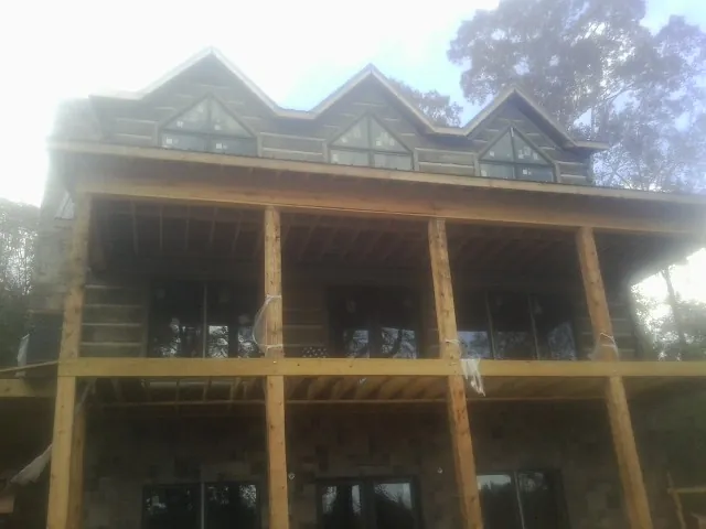 Dormers and porch framing on a large log home under construction — Roof Coating work by our crew in Fallsburg