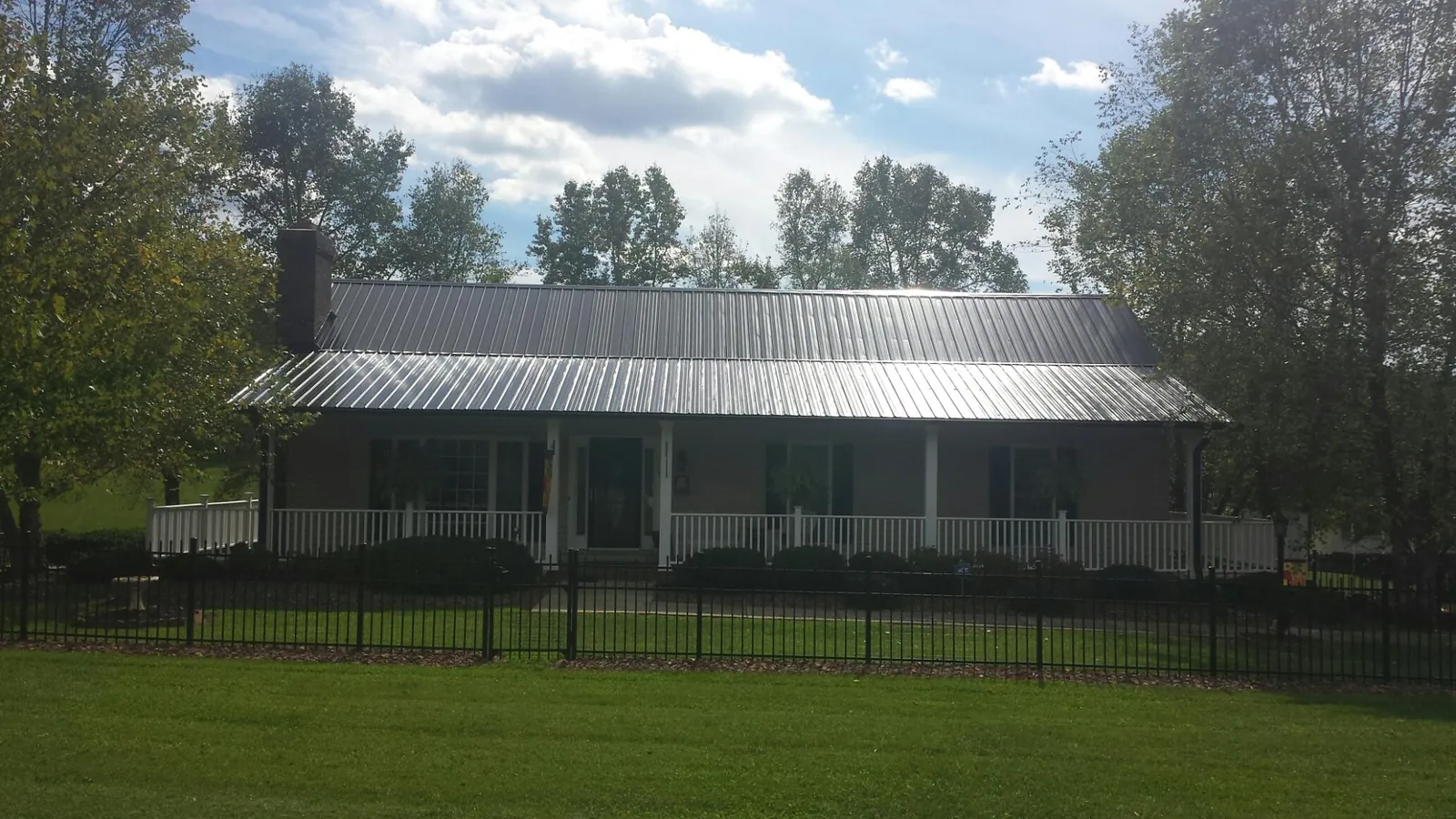 Gray metal roof on a brick ranch with a full width front porch — Gutter Guard Installation work by our crew in Fallsburg