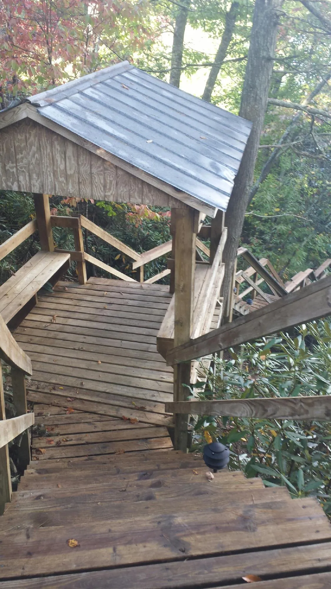 Metal roofed shelter over wooden steps on a wooded walkway — Skylight Repair & Installation work by our crew in Fallsburg