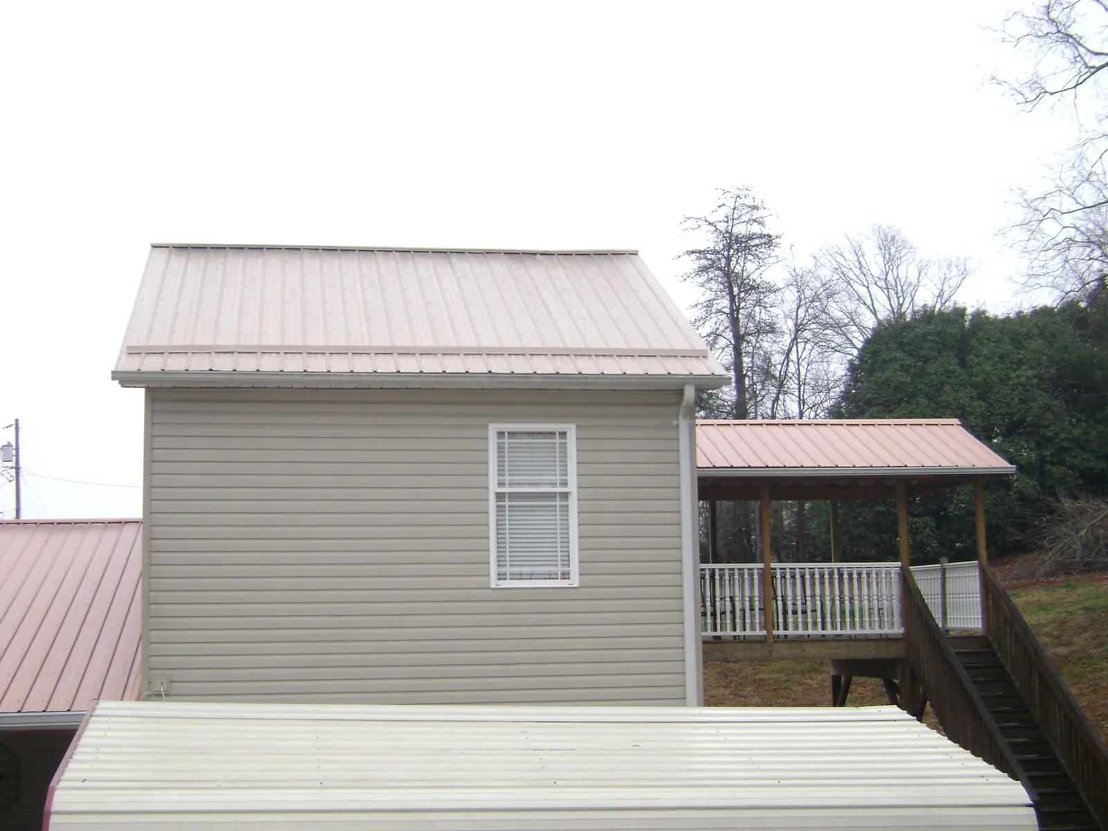 Tan metal roofs on a two story addition and attached porch, from a Roof Replacement job in Fallsburg