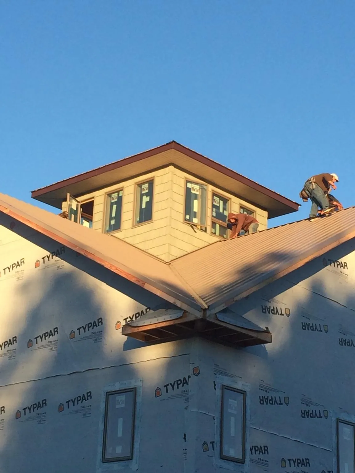 Roofers working around a rooftop cupola on a new metal roof at sunset — Roof Waterproofing in Fallsburg by Roofing Brothers